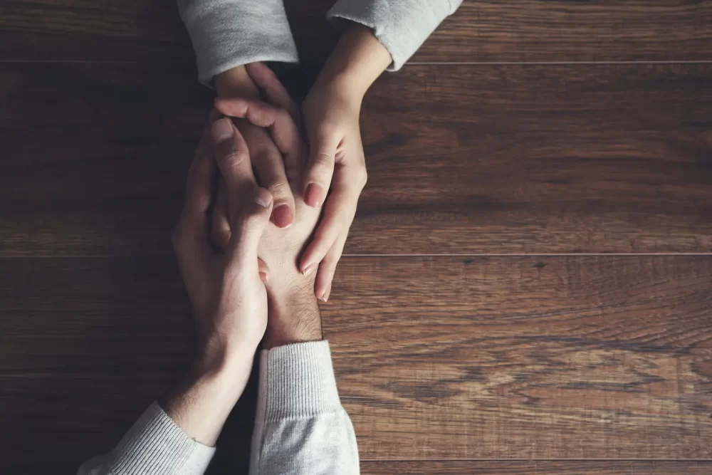 A woman holding the hand of a man with methadone maintenance