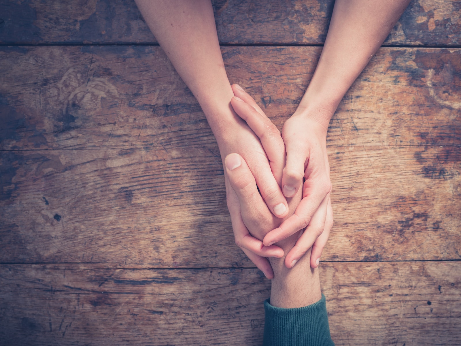 A woman holding the hand of an addict recover man