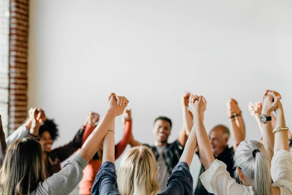 A group of people holding their hands up in the air.