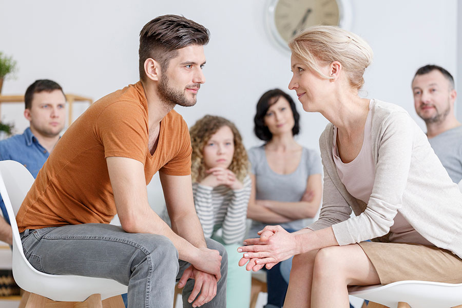 Two people in detox smile at each other during a group therapy session.