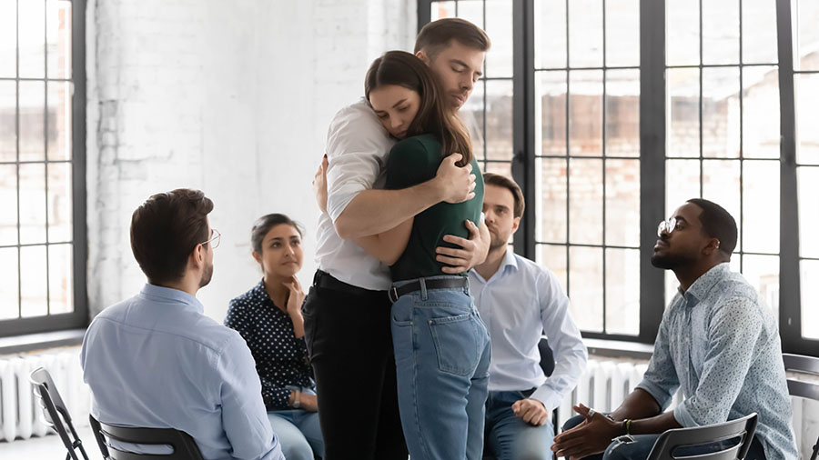 Two family members hug during a group therapy session.