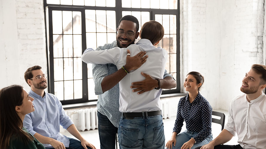 wo members hug during a support group meeting.