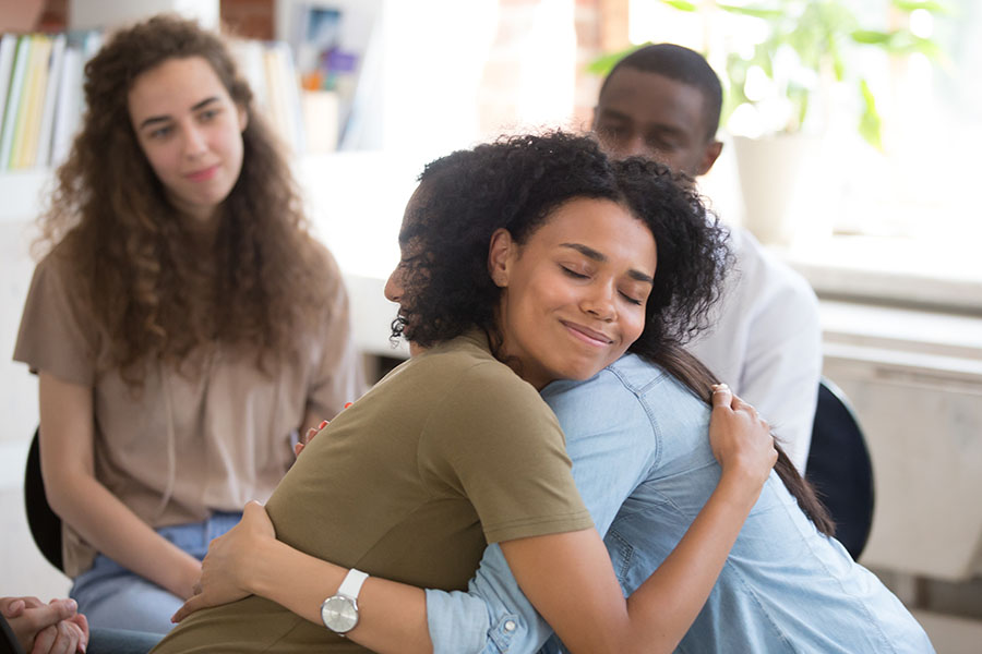 Two family members embrace during a group therapy session.