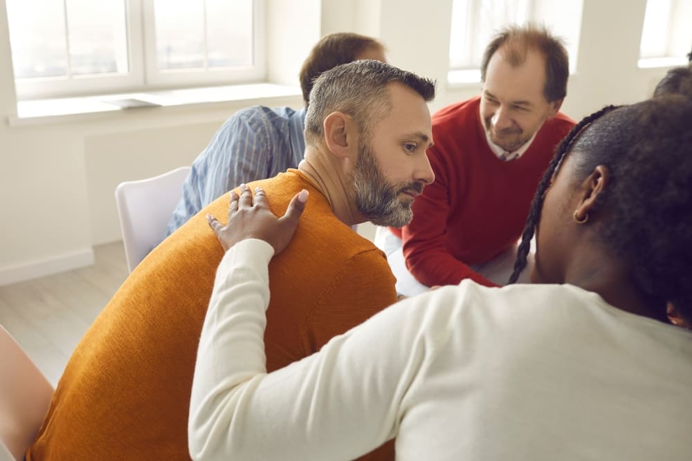 A person consoling another in group therapy