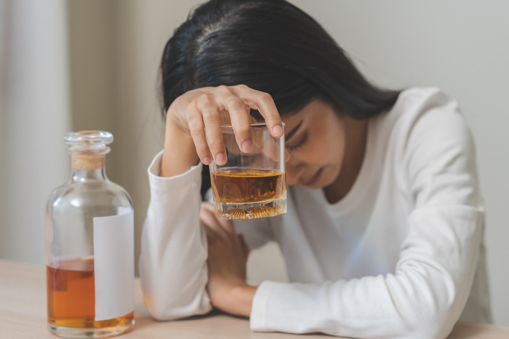 A sad woman holding an alcoholic drink