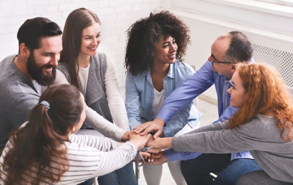 People at group therapy joining hands