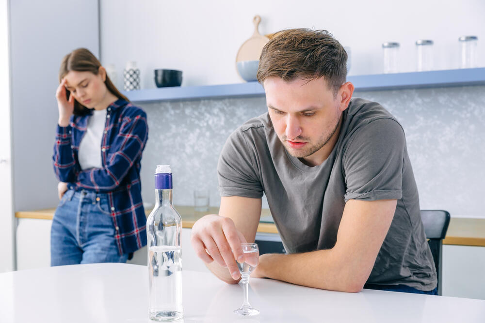 A couple in a fight while the man drinks alcohol