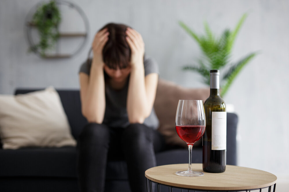 An upset woman sitting near a glass of wine