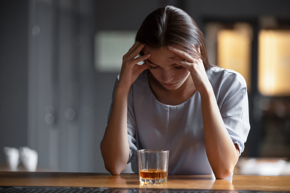 Depressed woman looking at a drink 