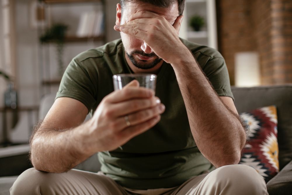 A man in pain holding a drink